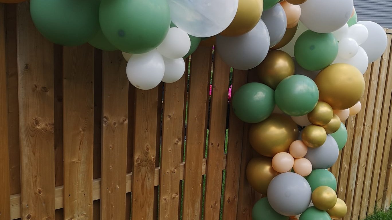 A single balloon garland running the length of a wooden fence