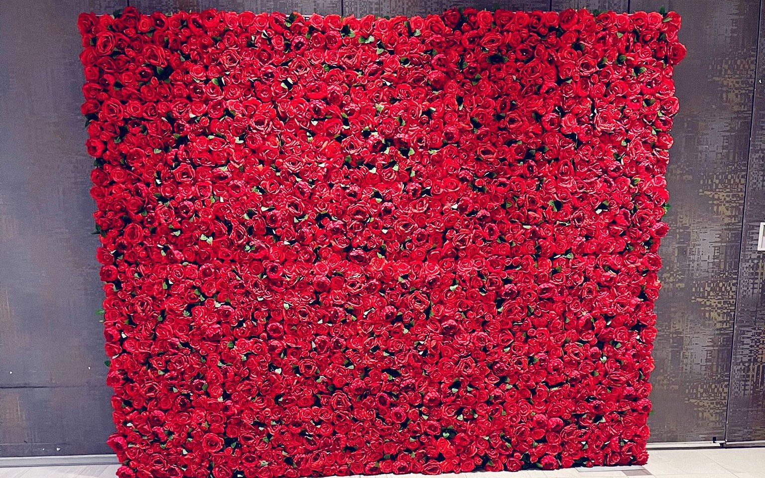 A red rose flower wall against dark bronze panelling in a pale-floored lobby